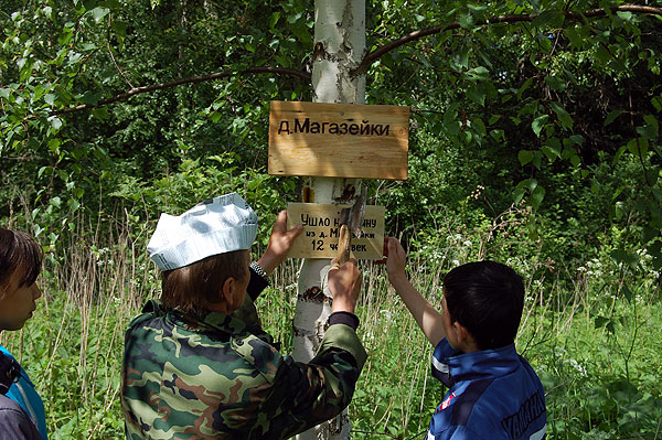 Заколачивание таблички в берёзку в исчезнувшей деревне Магазейки