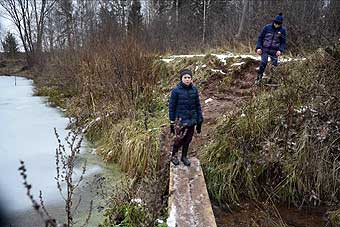Мальчики спускаются с дороги к пруду в обход обвалившегося моста